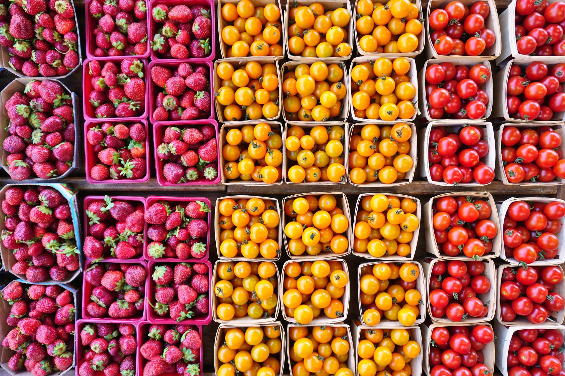 Close up of punnets of strawberries, yellow tomatoes and red tomatoes.